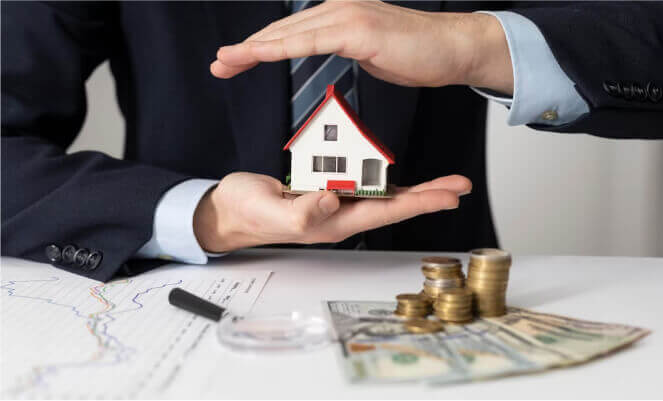 man holding model house with cash on table in front