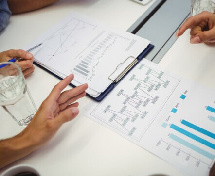 graphs and paper on table with people reviewing