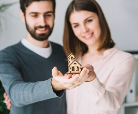 Couple holding model home in front of them