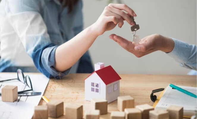 Person handing house key to another person.