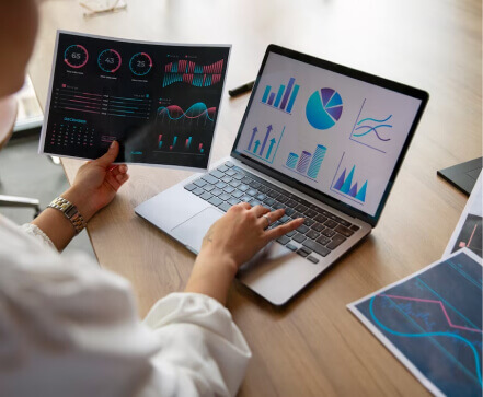 woman looking at graphs on paper and laptop