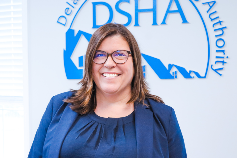 Headshot of new Chief of Staff Emily Cunningham in front of DSHA's logo.