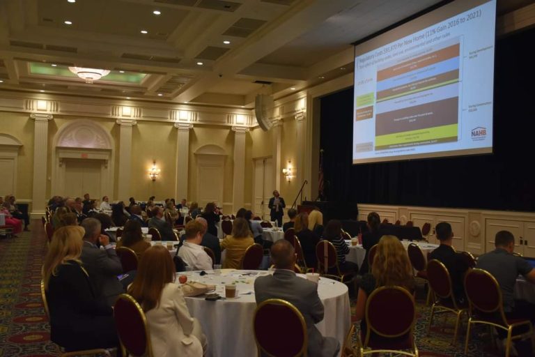 A large room of conference attendees listening to a presentation.