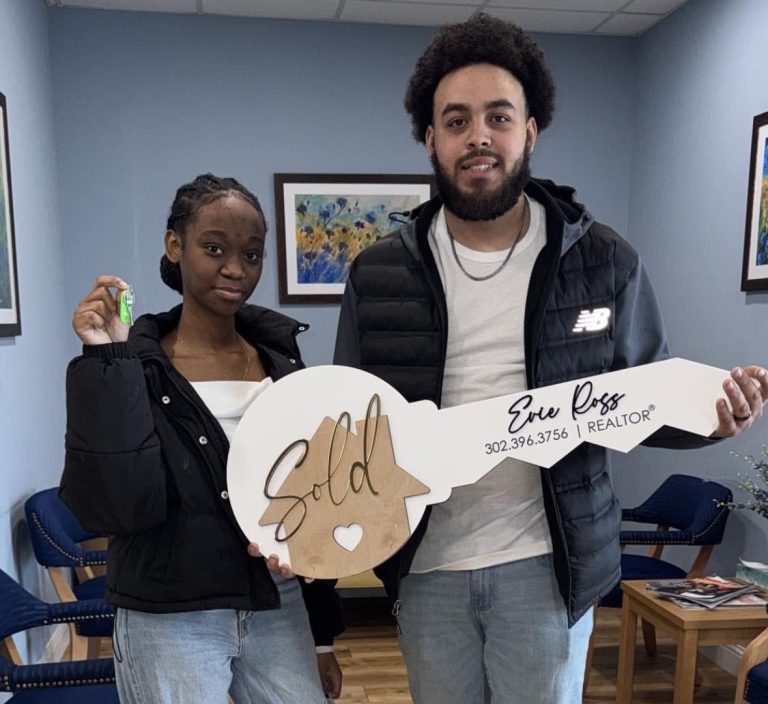 Syiarah Dupont and Taevon Cottman holding a key sign to celebrate the purchase of their house.