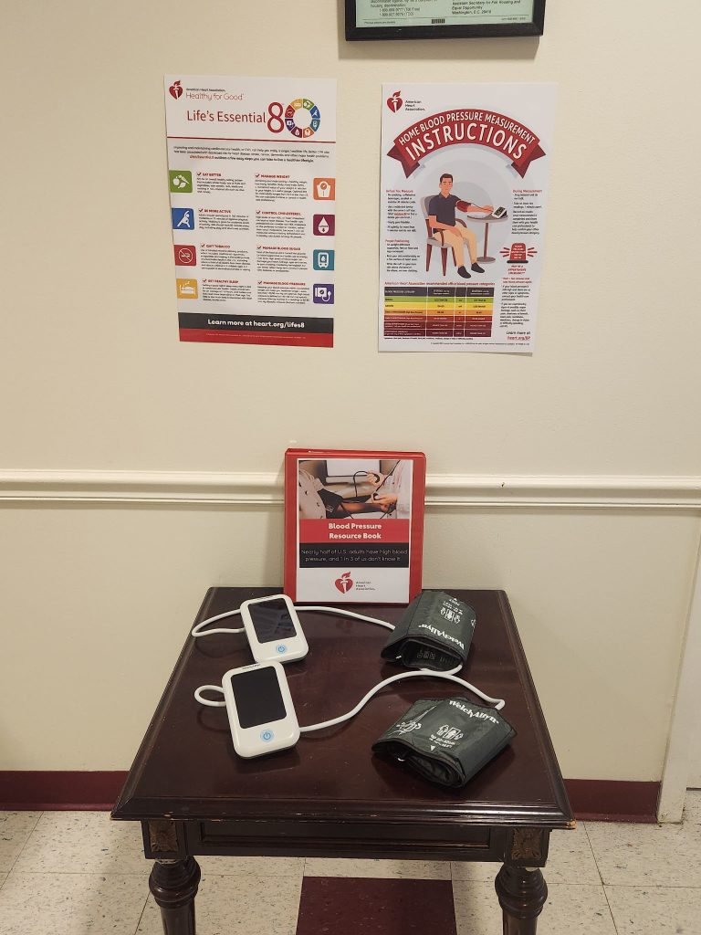 Two blood pressure cuffs at a station with posters about heart health.