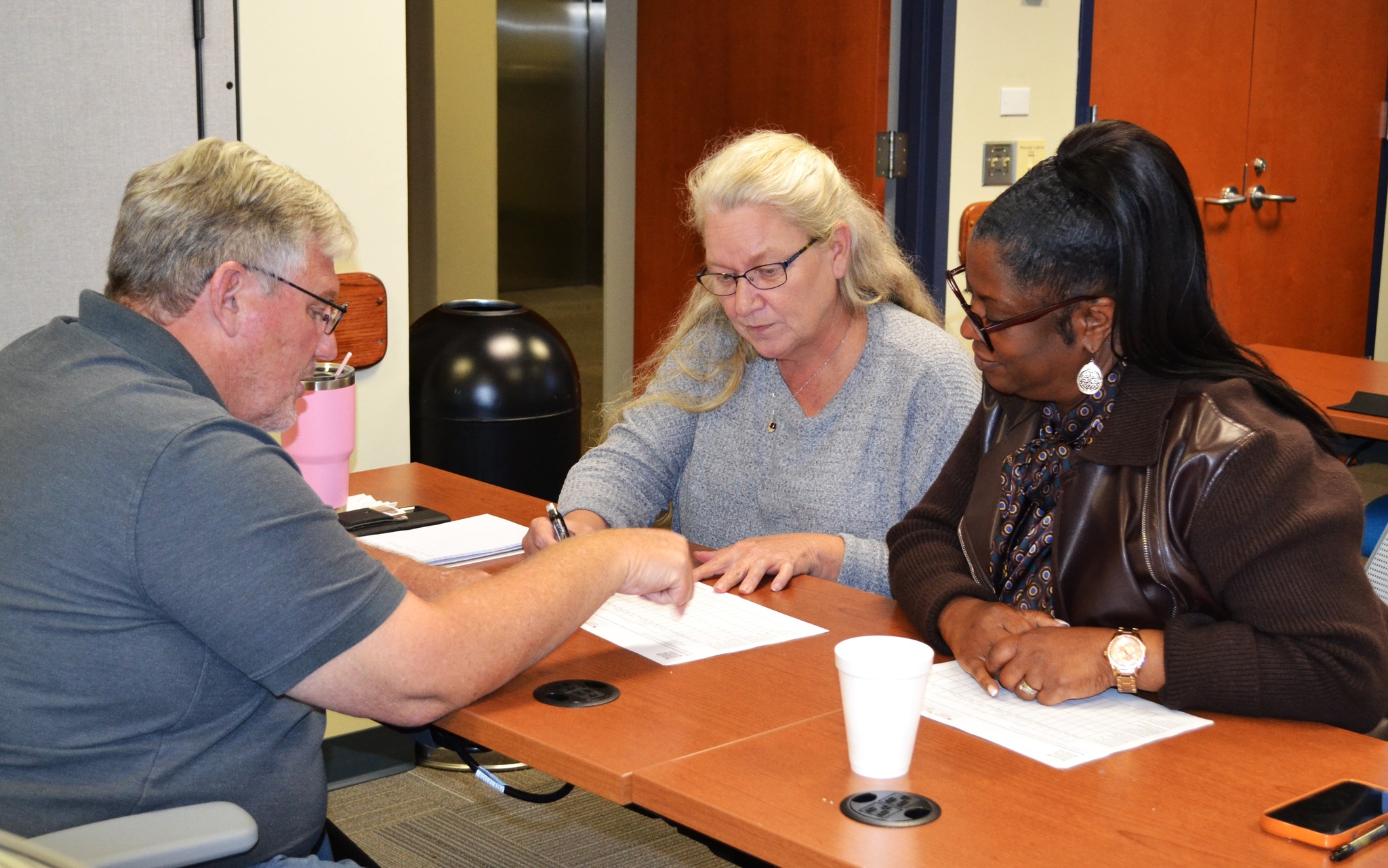 Three Task Force partners seated at a table, reviewing and discussing planning worksheets together